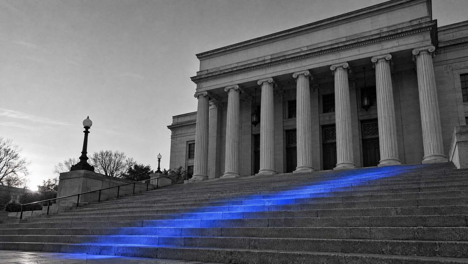 Stone courthouse columns and wide steps in black and white, with soft blue light falling across the steps.